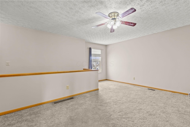 carpeted empty room with baseboards, a textured ceiling, visible vents, and a ceiling fan