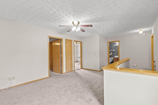 unfurnished room featuring ceiling fan, carpet floors, a textured ceiling, and baseboards