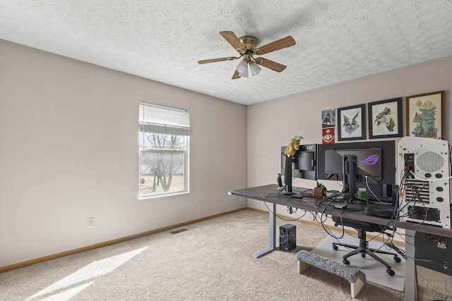 carpeted office featuring a ceiling fan, a textured ceiling, and baseboards