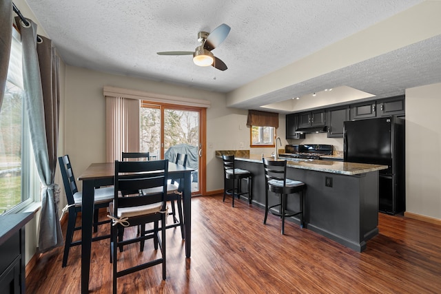 dining space featuring a textured ceiling, dark wood-type flooring, and baseboards