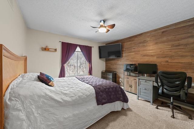 bedroom with wooden walls, light carpet, ceiling fan, and a textured ceiling