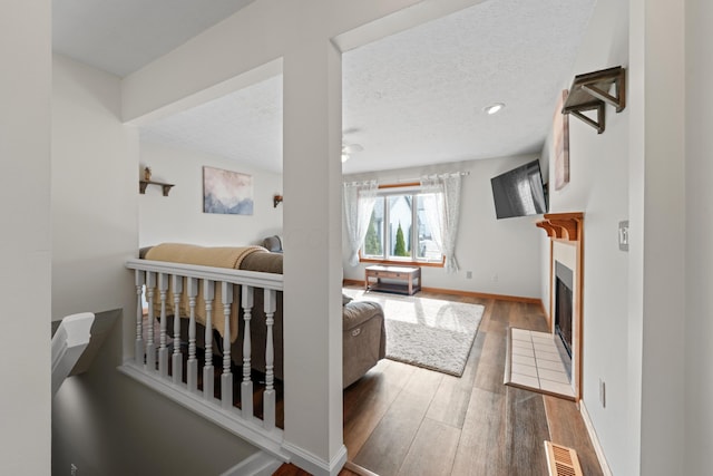 interior space featuring visible vents, a textured ceiling, a tiled fireplace, and wood finished floors