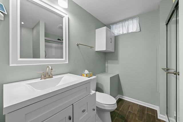 full bath with toilet, wood tiled floor, baseboards, and vanity