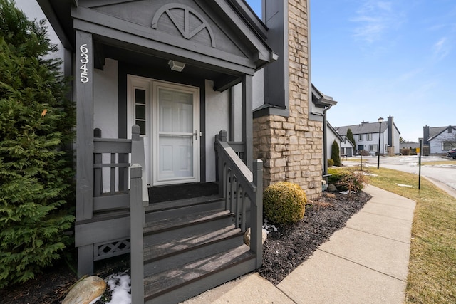 property entrance with stone siding, a chimney, a residential view, and stucco siding