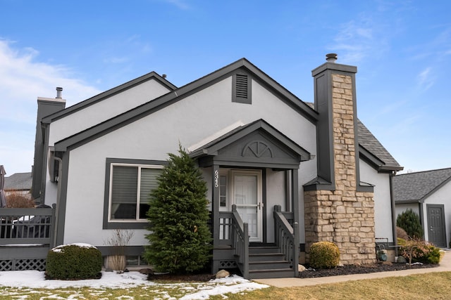 view of front of house featuring stone siding, a chimney, and stucco siding