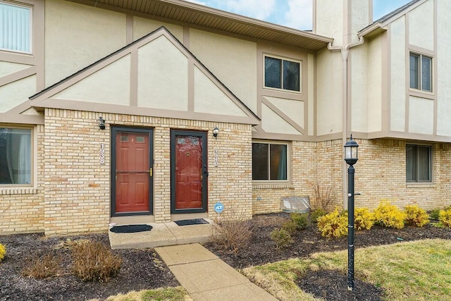 property entrance with brick siding and stucco siding