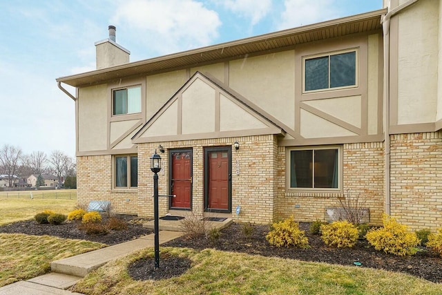 view of front of property with brick siding, a chimney, and stucco siding