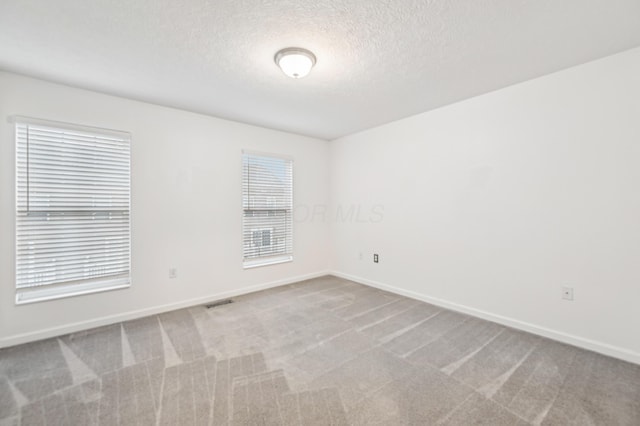 spare room featuring a textured ceiling, baseboards, and carpet flooring