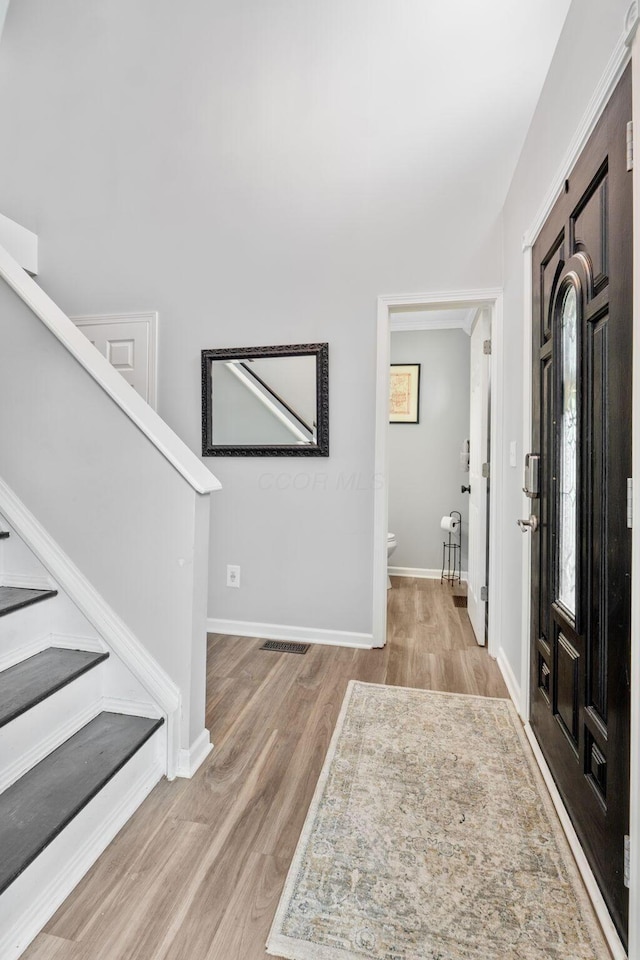 foyer entrance featuring light wood-style floors, visible vents, stairway, and baseboards