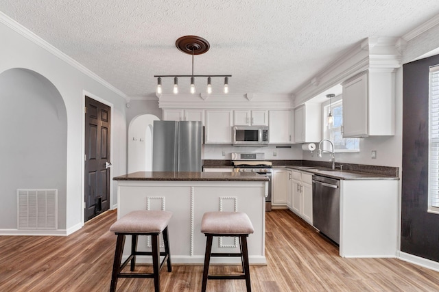 kitchen featuring pendant lighting, visible vents, appliances with stainless steel finishes, white cabinetry, and a kitchen island