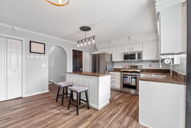 kitchen featuring stainless steel appliances, a sink, white cabinetry, a center island, and pendant lighting