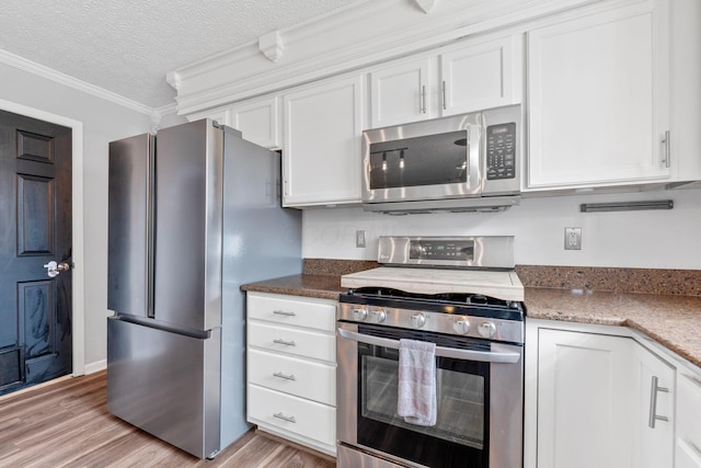 kitchen with crown molding, appliances with stainless steel finishes, stone countertops, white cabinets, and a textured ceiling