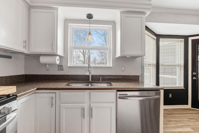 kitchen with white cabinets, dark countertops, decorative light fixtures, stainless steel appliances, and a sink