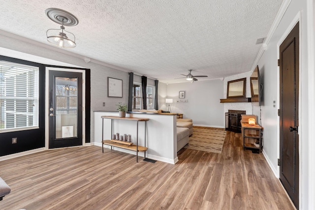 living room featuring light wood finished floors, a healthy amount of sunlight, visible vents, and crown molding