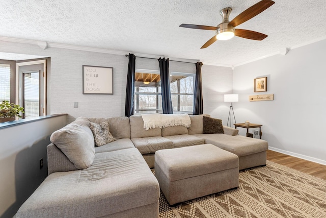 living area with a textured ceiling, wood finished floors, a ceiling fan, baseboards, and ornamental molding