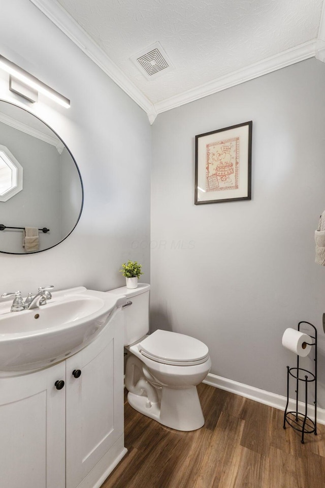 half bath featuring ornamental molding, visible vents, vanity, and toilet