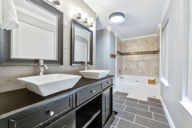 full bath with double vanity, a sink, a textured ceiling, and a bathing tub