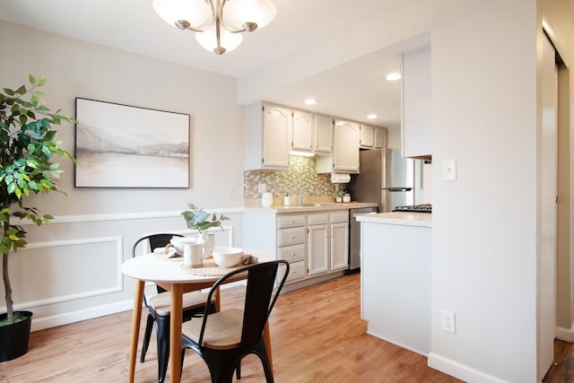 kitchen featuring light wood finished floors, light countertops, tasteful backsplash, and appliances with stainless steel finishes