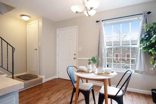 dining area featuring stairs, baseboards, a notable chandelier, and light wood-style floors