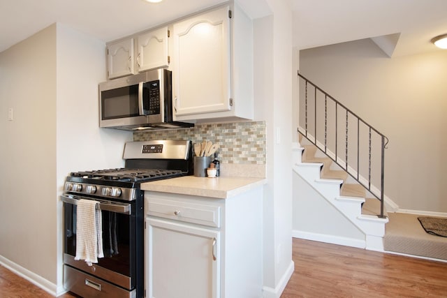 kitchen featuring light wood-style flooring, baseboards, light countertops, appliances with stainless steel finishes, and backsplash