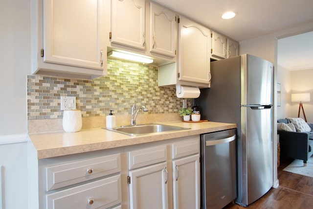 kitchen with appliances with stainless steel finishes, light countertops, a sink, and decorative backsplash