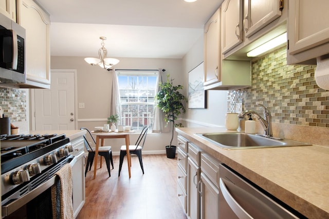 kitchen featuring light wood-style flooring, a sink, baseboards, light countertops, and appliances with stainless steel finishes