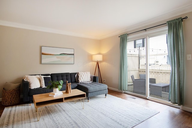 living area featuring baseboards, wood finished floors, and crown molding