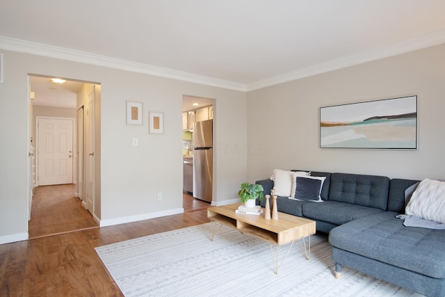 living area featuring crown molding, baseboards, and wood finished floors