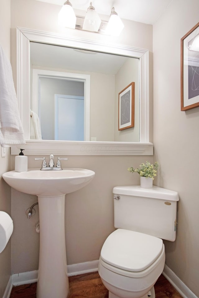 bathroom with wood finished floors, toilet, and baseboards