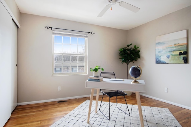 office area with ceiling fan, light wood finished floors, visible vents, and baseboards