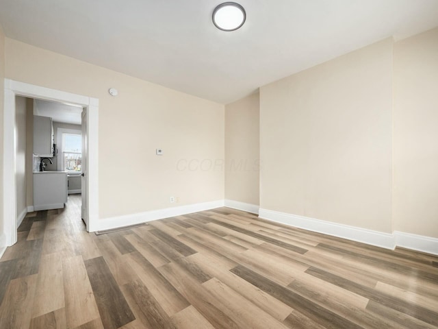 spare room featuring light wood-type flooring and baseboards