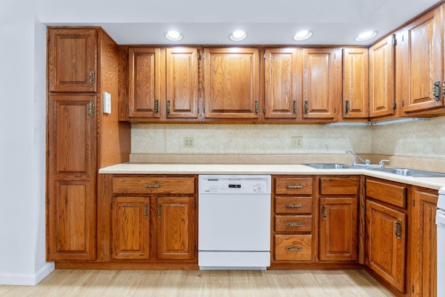 kitchen featuring dishwasher, a sink, and brown cabinets