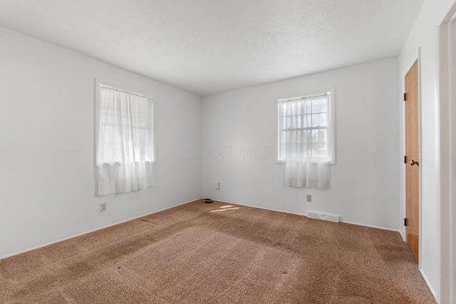 empty room featuring a textured ceiling, visible vents, and carpet flooring