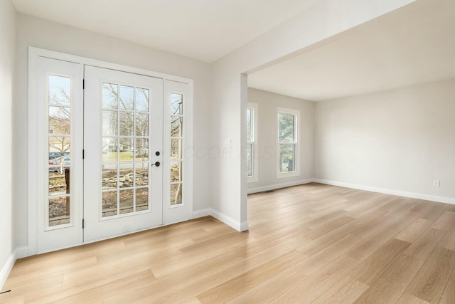 doorway featuring baseboards and light wood finished floors