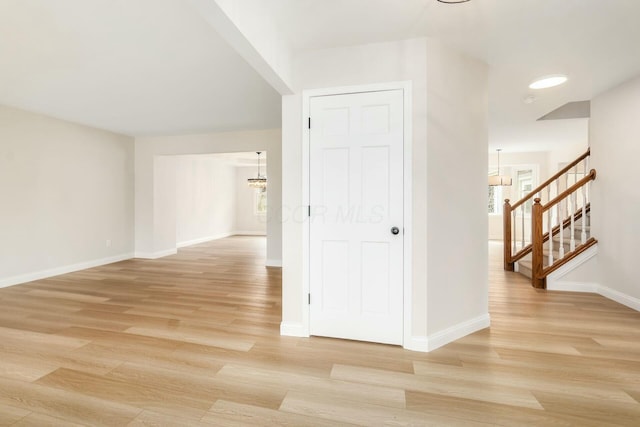 hallway featuring light wood-style flooring, stairway, and baseboards