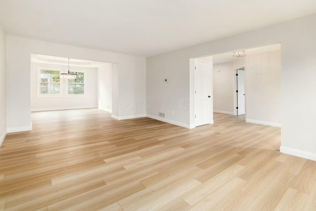 unfurnished room with visible vents, light wood-style flooring, and baseboards