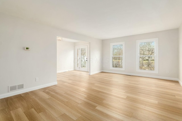 spare room with light wood-style floors, baseboards, and visible vents