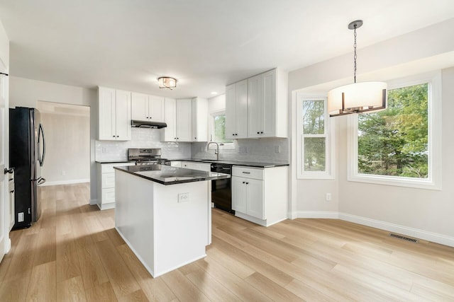 kitchen featuring black dishwasher, visible vents, freestanding refrigerator, under cabinet range hood, and stainless steel gas range oven