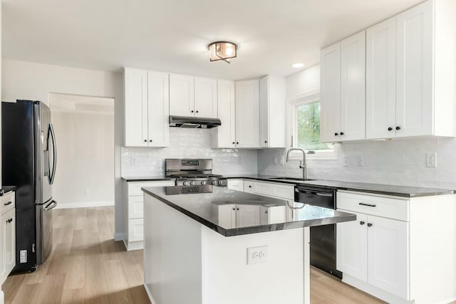 kitchen featuring appliances with stainless steel finishes, dark countertops, a sink, and under cabinet range hood