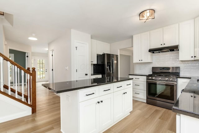 kitchen featuring stainless steel gas stove, light wood finished floors, decorative backsplash, under cabinet range hood, and refrigerator with ice dispenser