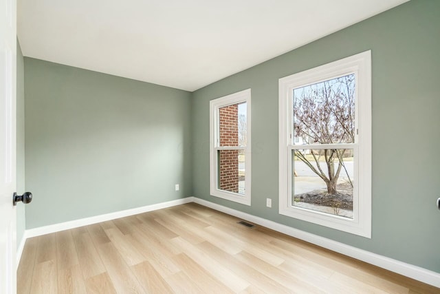 unfurnished room with visible vents, light wood-style flooring, and baseboards