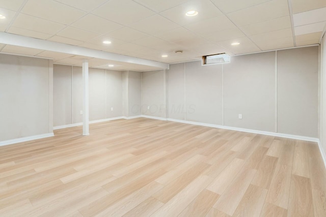 finished below grade area with a paneled ceiling, light wood-style flooring, and recessed lighting