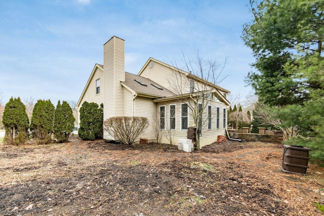 view of side of property featuring a shingled roof and a chimney