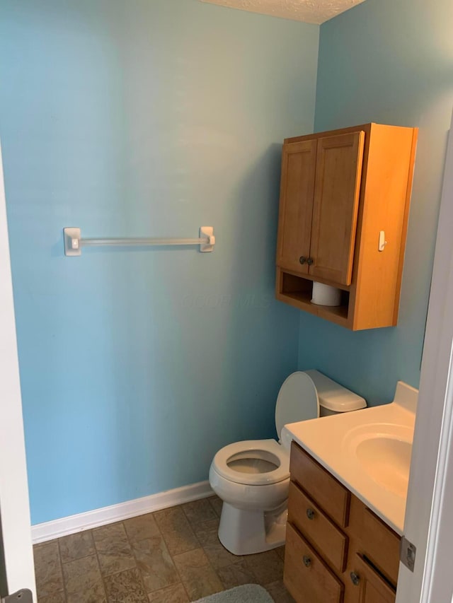 bathroom with toilet, baseboards, a textured ceiling, and vanity