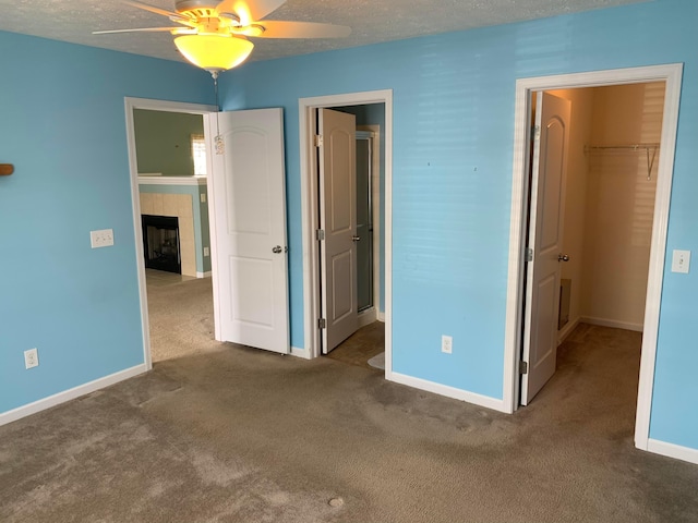 unfurnished bedroom featuring carpet floors, a fireplace, a closet, a spacious closet, and baseboards