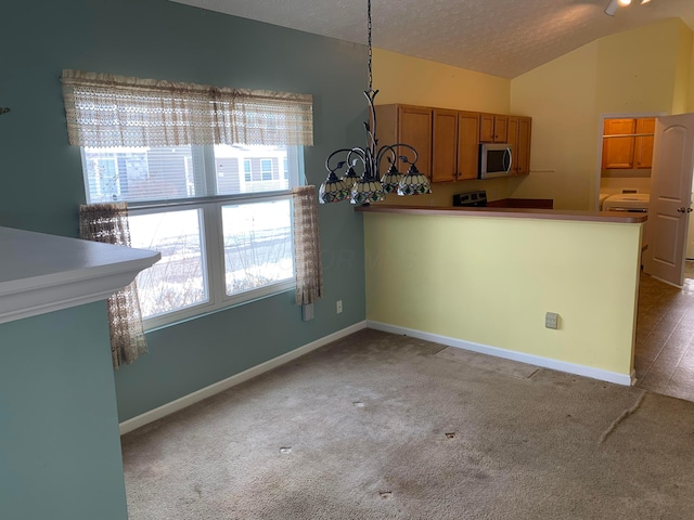 kitchen with carpet floors, lofted ceiling, stainless steel microwave, hanging light fixtures, and brown cabinetry