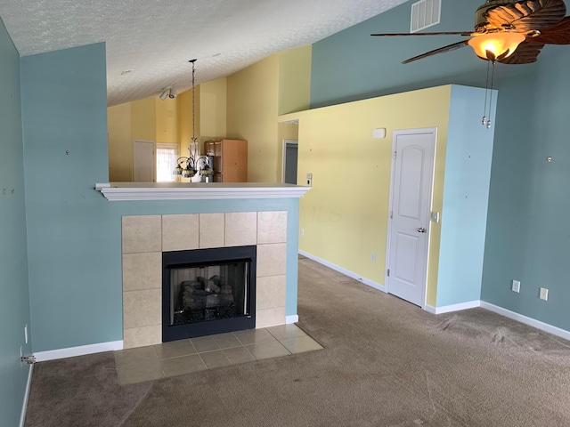 unfurnished living room with a textured ceiling, light colored carpet, visible vents, vaulted ceiling, and a tiled fireplace