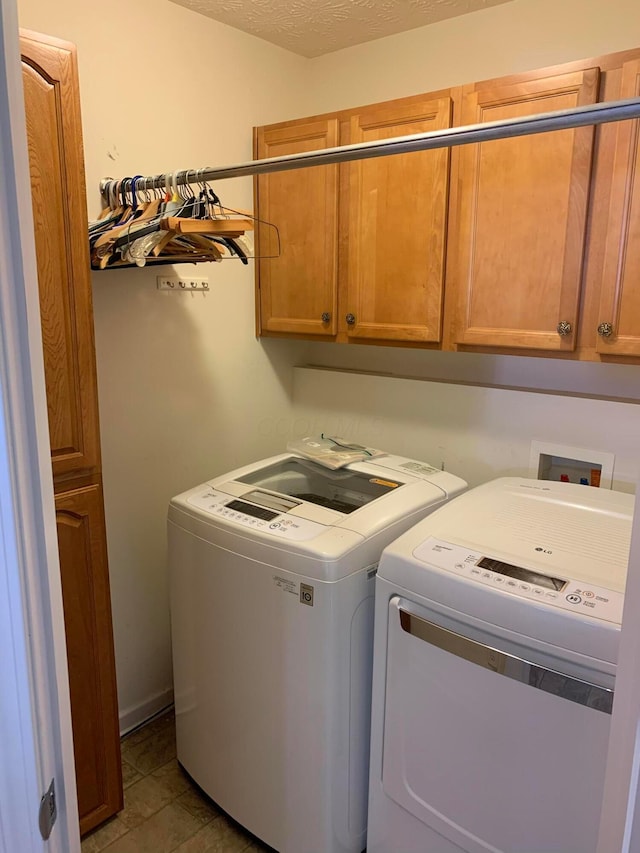 clothes washing area featuring a textured ceiling, independent washer and dryer, and cabinet space