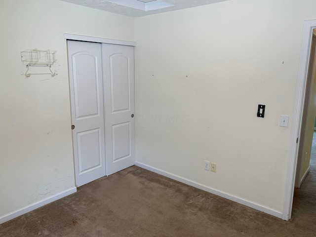 unfurnished bedroom with a closet, carpet flooring, and baseboards