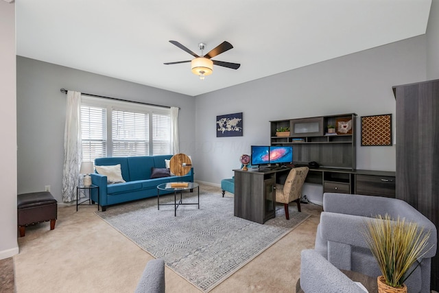 living area featuring baseboards, a ceiling fan, and light colored carpet